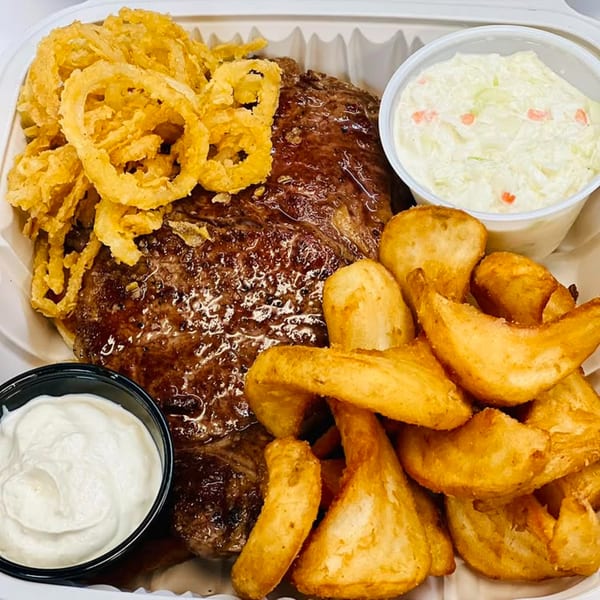 Chefhouse American cuisine: steak with onion rings, potato wedges, coleslaw, and sour cream.