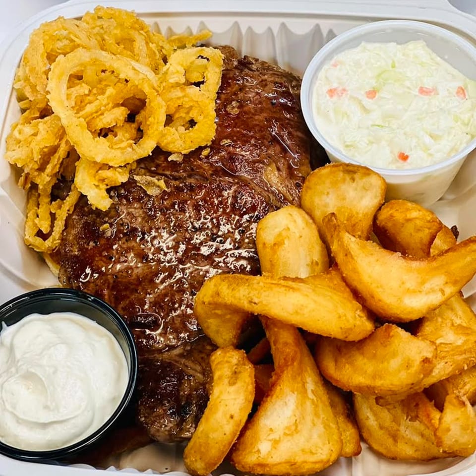 Chefhouse American cuisine: steak with onion rings, potato wedges, coleslaw, and sour cream.