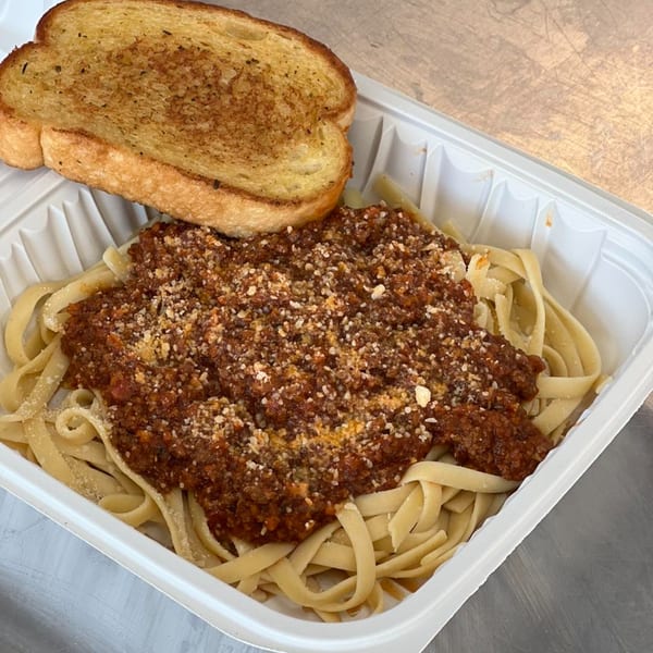Chefhouse American cuisine: Fettuccine pasta with meat sauce and a side of garlic bread in a takeout container.