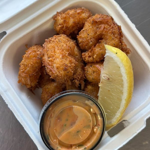 Chefhouse's crispy fried shrimp with a lemon wedge and dipping sauce in a white takeout container.
